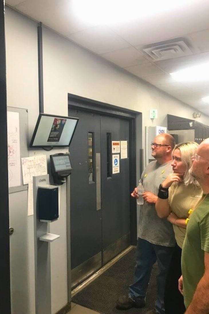 Crown Cork employees looking at digital signage