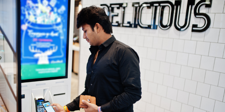 A man talking on a phone, using digital signage.