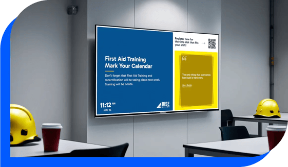 A TV dashboard wall mounted in a large office setting showing a first aid training notification