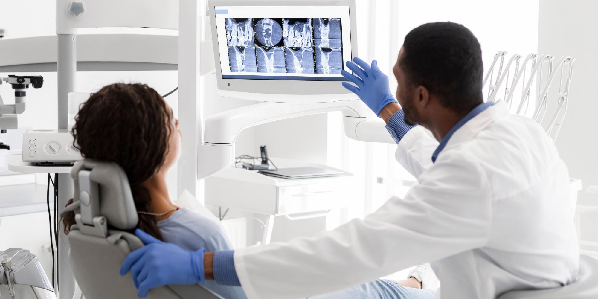 A dentist pointing at a digital sign for his patient in his clinic.