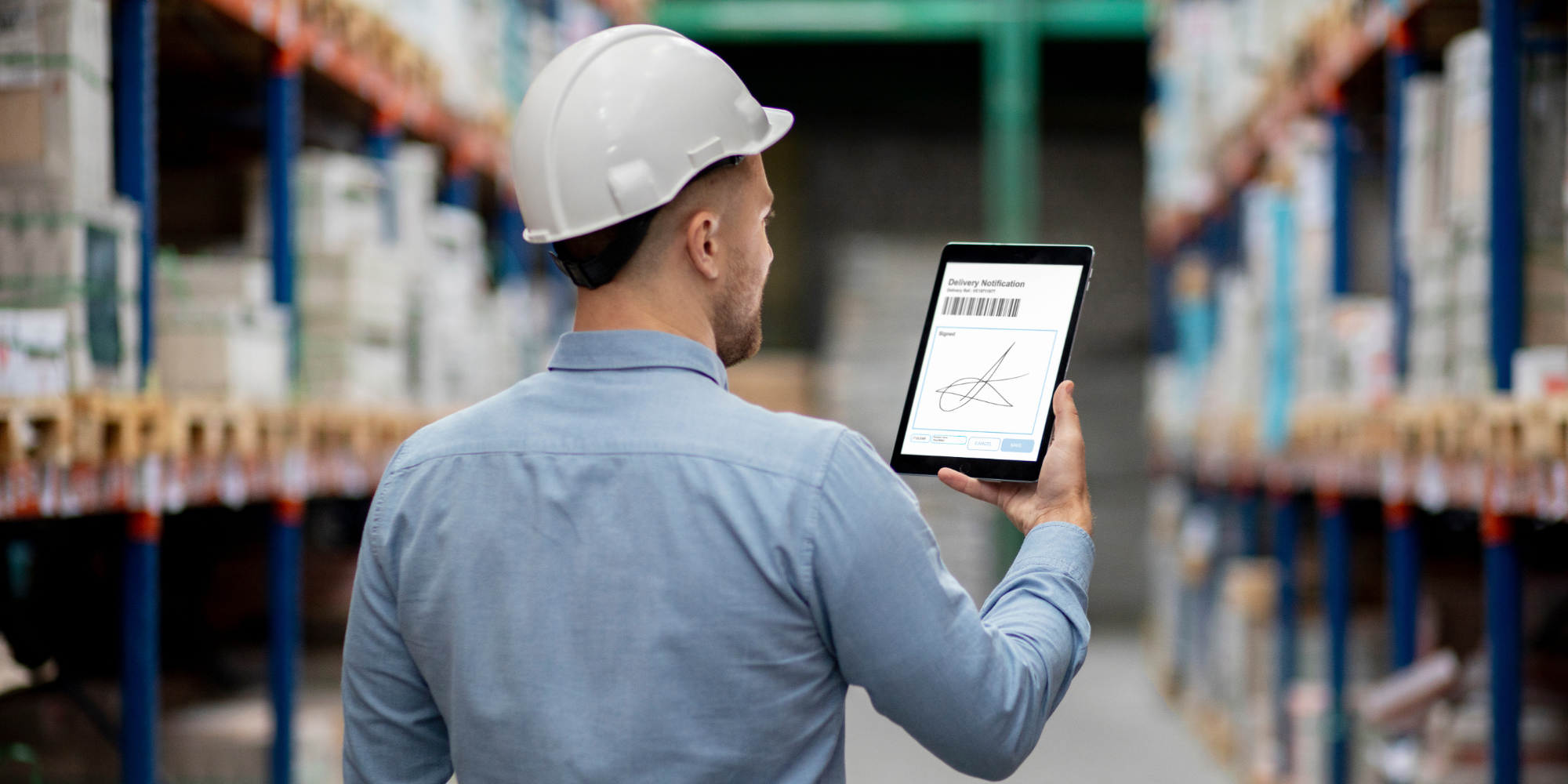 A man holding a tablet in the warehouse.